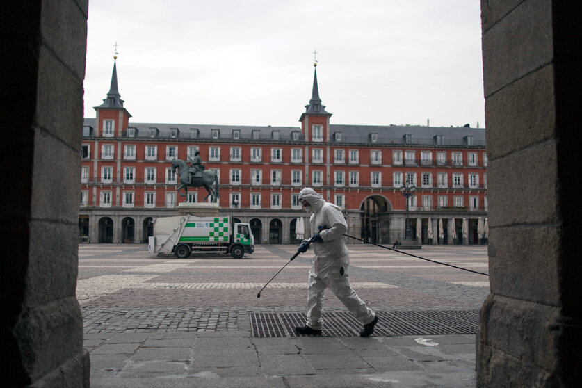 A cleaner worker cleans the pavement of Plaza Mayor square in Madrid downtown, Spain, Wednesday, March 18, 2020. Spain will mobilize 200 billion euros or the equivalent to one fifth of the country's annual output in loans, credit guarantees and subsidies for workers and vulnerable citizens, Prime Minister Pedro Sánchez announced Tuesday. For most people, the new coronavirus causes only mild or moderate symptoms. For some, it can cause more severe illness, especially in older adults and people with existing health problems. (AP Photo/Manu Fernandez)